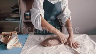 一个穿围裙的女陶工准备和滚泥
